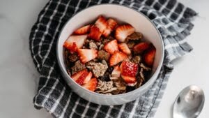 A bowl of cereal with strawberries on top.