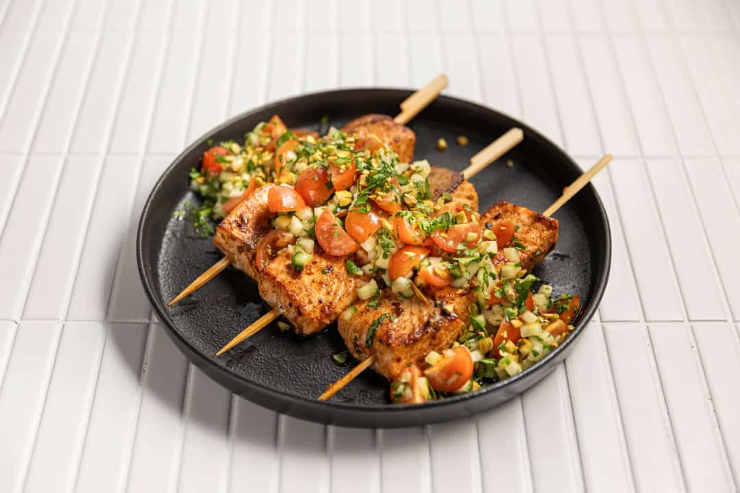 A gluten free dish consisting of salmon skewers topped with a summer salsa.