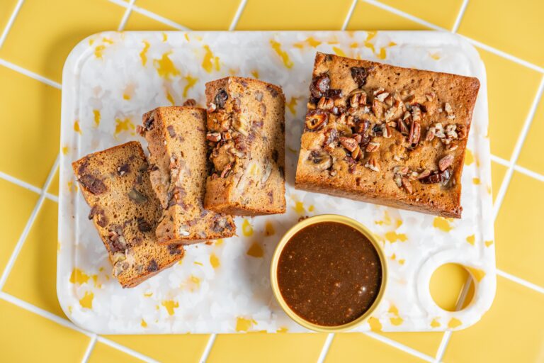 Gluten free sticky date banana bread topped with salted caramel sauce and pecans